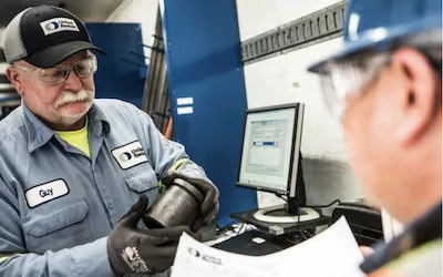 dos trabajadores que conversan sobre el repuesto de un equipo en un mostrador