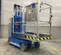 Front angled view of a blue Genie one-person lift with safety rail, in an indoor work zone.