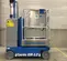 Side view of a blue Genie one-person lift with safety rail, in an indoor work zone.