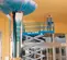 Side view of an extended blue Genie scissor lift with an operator using the platform working on the ceiling indoors.
