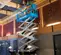 Side view of an extended blue Genie scissor lift elevated indoors with an operator working on the ceiling.