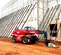 Side view of a red Magni telehandler with an enclosed cabin and boom retracted on a construction site.