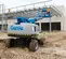 Rear view of a blue Genie boom lift with two workers on the platform elevated on a construction site.