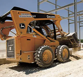 cargador compacto amarillo john deere en sitio de trabajo delante de estructura de andamios