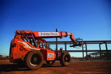 Montacargas JLG naranja con la marca de United Rentals contra un cielo azul