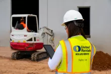 mujer en un lugar de trabajo sosteniendo un ipad junto a un cargador compacto