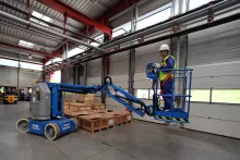 Trabajador en una brazo de elevación eléctrico dentro de un almacén