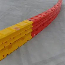 Water-filled safety barriers lined up along a road construction site to manage traffic and protect workers.